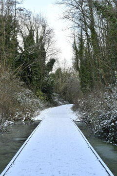 Passage sur caillebotis enneig&eacute; au dessus d'une marre prise par les glaces sur le Ravel &agrave; &Eacute;caussinnes d'Enghien (Soignies)