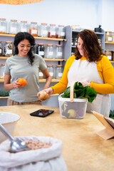 Shopkeeper weighing fresh produce for customer in zero waste store
