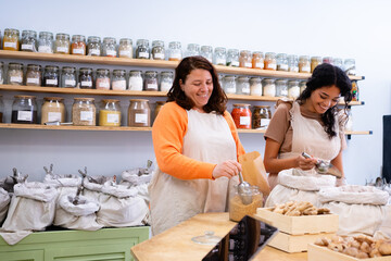 Shopkeepers filling paper bag with dried foods in zero waste store