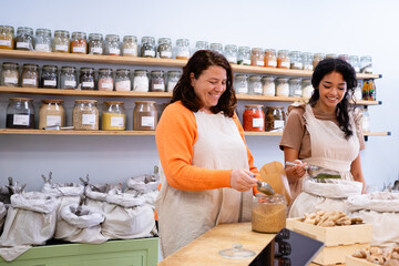 Shopkeepers serving customers, filling paper bags with dried foods in zero waste store