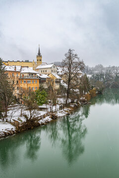 Winter view of the historic Breg riverbank houses and St. Nicholas Cathedral reflected in the Krka River during a snowy Christmas day in the old town