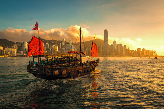 Awesome sunset view of a brightly illuminated junk boat in Victoria Harbour in front of Hong Kong's fantastic skyline with its impressive skyscrapers