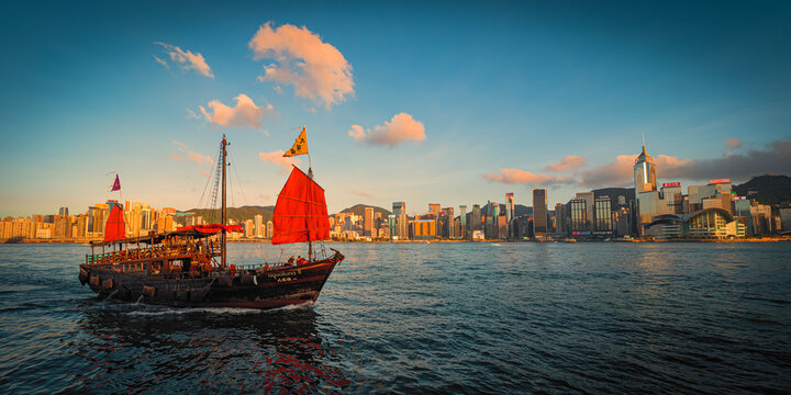 Awesome day view of a tourist junk boat in Victoria Harbour in front of Hong Kong's fantastic skyline and impressive skyscrapers
