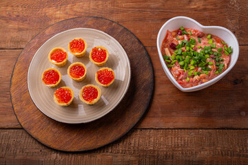 Red caviar tartlets on a plate and a heart-shaped salad with chicken and beans