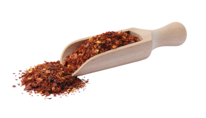 Wooden scoop containing red pepper flakes and some scattered around it on a plain background isolated on white