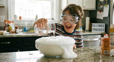 A boy pours water into a bowl, creating a bubbly scene in his kitchen.