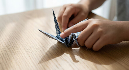 A person builds an origami figure on a wooden table in natural light during the afternoon.
