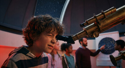 A boy looks through a telescope during an astronomy class while others watch.