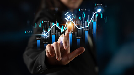 A business professional interacts with financial data through digital graphs and charts,...