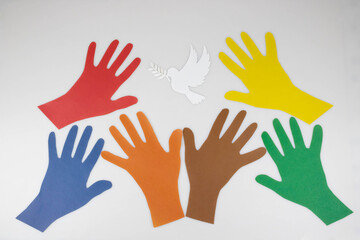 Colored paper hands reach out to a paper dove on a white background. World Peace Day. World Science Day for Peace and Development.