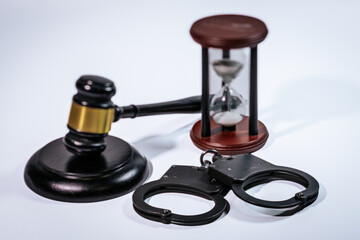 Gavel, hourglass, and handcuffs arranged on a smooth surface, symbolizing justice, time, and law...