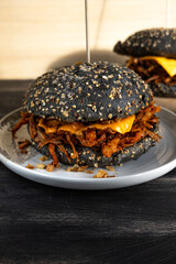 Vegan pulled mushroom burger with black bun on dark background