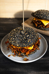 Vegan pulled mushroom burger with black bun on dark background