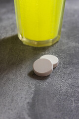 Effervescent tablet on table with glass. Dietary supplement with magnesium and vitamins