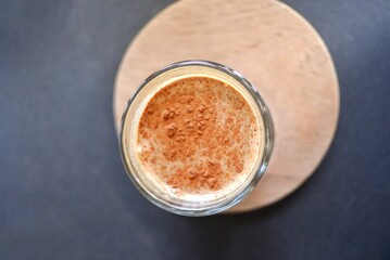 A cup of dirty coffee on a wooden tray,a black table background with top view
