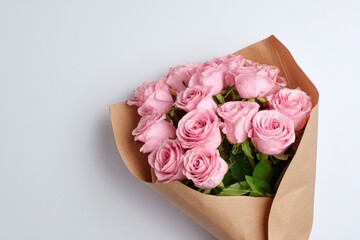 Bouquet of fresh pink roses wrapped in brown paper on white background