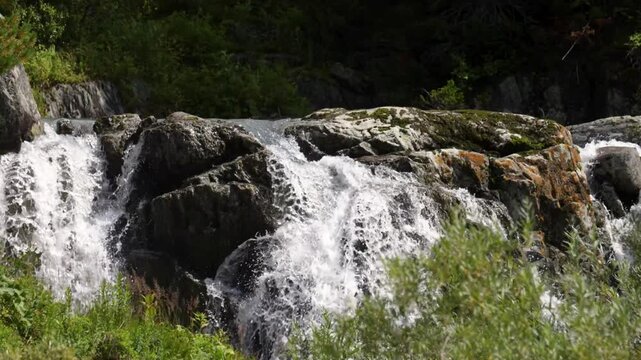 A large waterfall in the Altai Mountains, falling into the valley from high cliffs