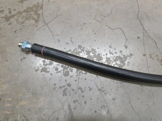 Industrial Rubber Hose with Metal Fitting on Concrete Surface