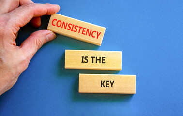 Consistency is the key symbol. Concept words Consistency is the key on beautiful wooden blocks. Beautiful blue background. Businessman's hand. Business consistency is the key concept. Copy space.