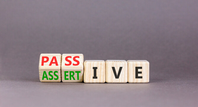 Passive or assertive symbol. Concept words Passive or Assertive on beautiful wooden cubes. Beautiful grey table grey background. Business passive or assertive concept. Copy space