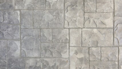 A detailed close-up of a grey stamped concrete surface, designed with an irregular stone block...