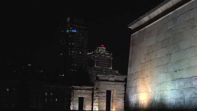 Madrid, Spain - December 30, 2025:  Templo de Debod. A city skyline at night with a red building in the middle. The sky is dark and the buildings are lit up.
