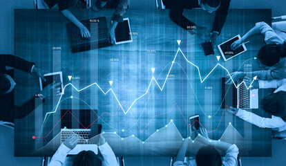 Professionals collaborate in a modern office to analyze market trends and financial data using laptops and tablets, showcasing a dynamic business environment. Scalp