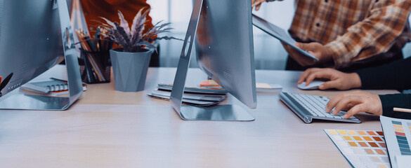 A dynamic team engages in collaboration and discussion around modern desktop computers in a bright office environment, showcasing creativity and teamwork. SACTR