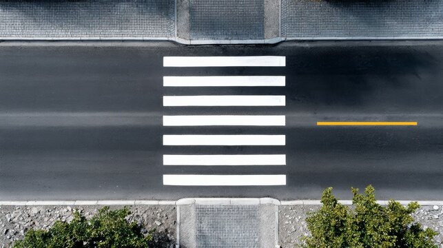 A street with a crosswalk and a yellow line. The street is empty and the crosswalk is not in use