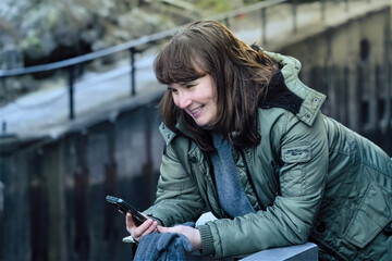 Digital balance concept with adult woman checking her smartphone during slow outdoor pause, combining mindful technology use, independence, active ageing, sustainable living habits in everyday life
