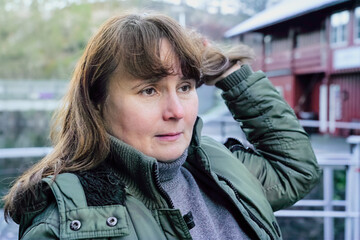 Mindful self awareness expressed as an adult woman touches her hair outdoors, pausing during a walk to reconnect with herself, reflecting slow living, emotional balance, active ageing in everyday life