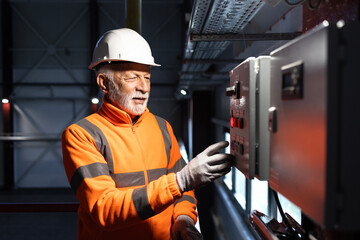 Senior engineer operating industrial control panel in factory