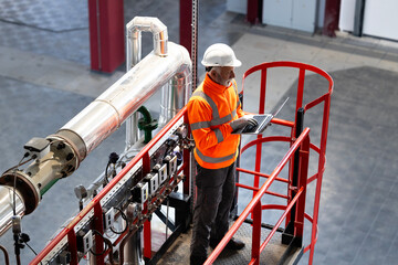 Engineer checking industrial plant system on laptop