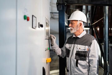 Senior engineer operating industrial control panel in factory