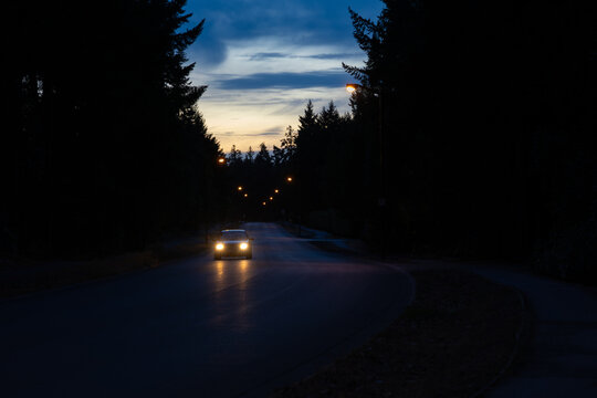 Car driving in the dark with lights, during the late golden hour
