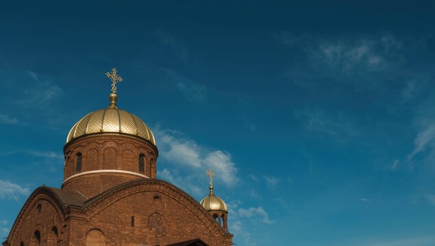 Historical brick church featuring a golden dome and cross, background of clear blue sky - Powered by Adobe