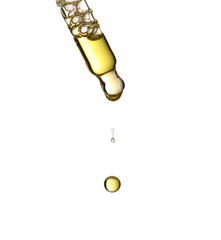 Studio shot of a glass pipette with golden cosmetic oil releasing separated drops, isolated on a white background