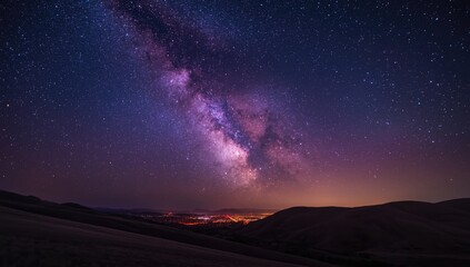 Obraz premium Night scene with a star-filled sky, hills, and a purple Milky Way over illuminated city lights, highlighting celestial beauty