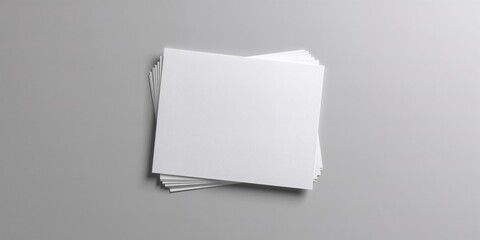 Multiple white paper sheets stacked for brochure layout on grey surface, emphasizing print preparation and design
