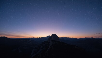 Night sky with stars and mountain silhouette during sunset, highlighting atmospheric lighting