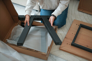 Mature woman assembling furniture at home