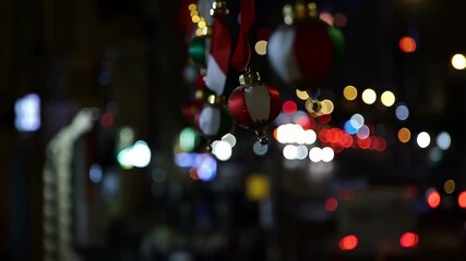 Colorful Christmas ornaments hanging with blurred city lights in the background. Festive decorations creating a joyful holiday atmosphere
