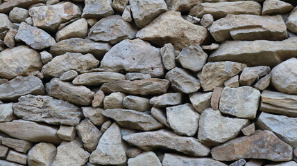 a fragment of a gray stone wall with large, solid boulders of varying shapes and sizes, with the rough texture of natural rock, part of the protective wall of an old fortress or a stylized version