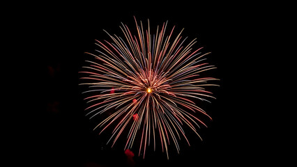Vibrant firework exploding in the night sky, showcasing a dazzling display of red, orange, and gold colors