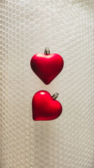 Two Red Heart Ornaments on Bubble Wrap Texture for Valentine's Day or Christmas