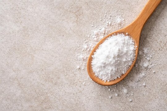 Overhead image of white boric acid powder in wooden spoon on rough textured surface with copy space