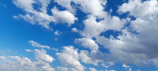 Clear blue sky background with scattered white cumulus clouds.