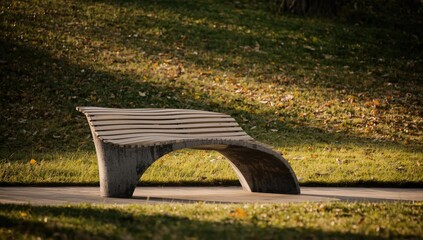 Concrete park bench with wooden slats featuring a curious curve, serving as urban furniture in autumn