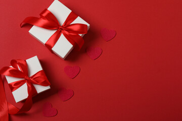 Festive background with a bottle of champagne, two glasses and hearts and gift boxes. A romantic date on Valentine's Day