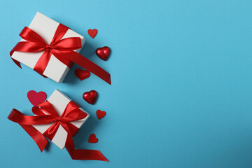 Festive background with a bottle of champagne, two glasses and hearts and gift boxes. A romantic...